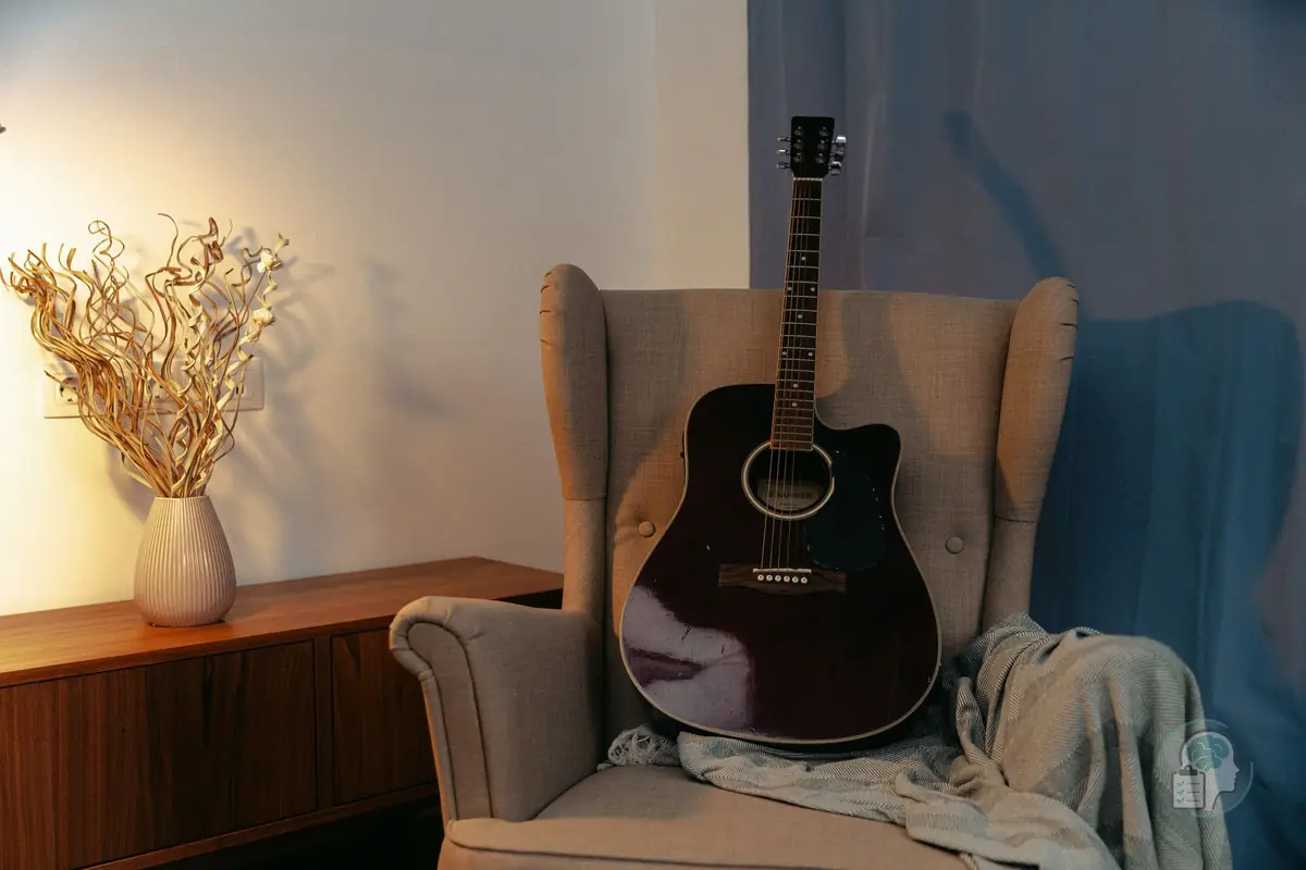 Guitarra acústica apoyada en un sillón sin nadie que la toque, una imagen de las aficiones que se abandonan con la anhedonia