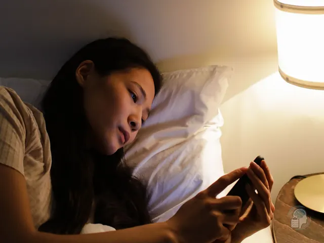 Mujer tumbada en la cama de noche mirando el móvil a la espera de un mensaje, una escena típica del apego ansioso