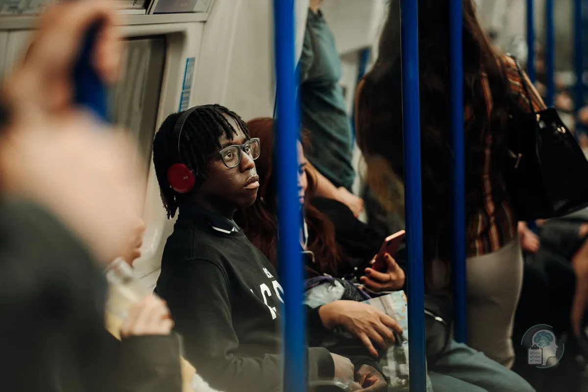 Jove amb auriculars en un vagó de metro ple de gent, una manera habitual de protegir-se del soroll en l'autisme adult