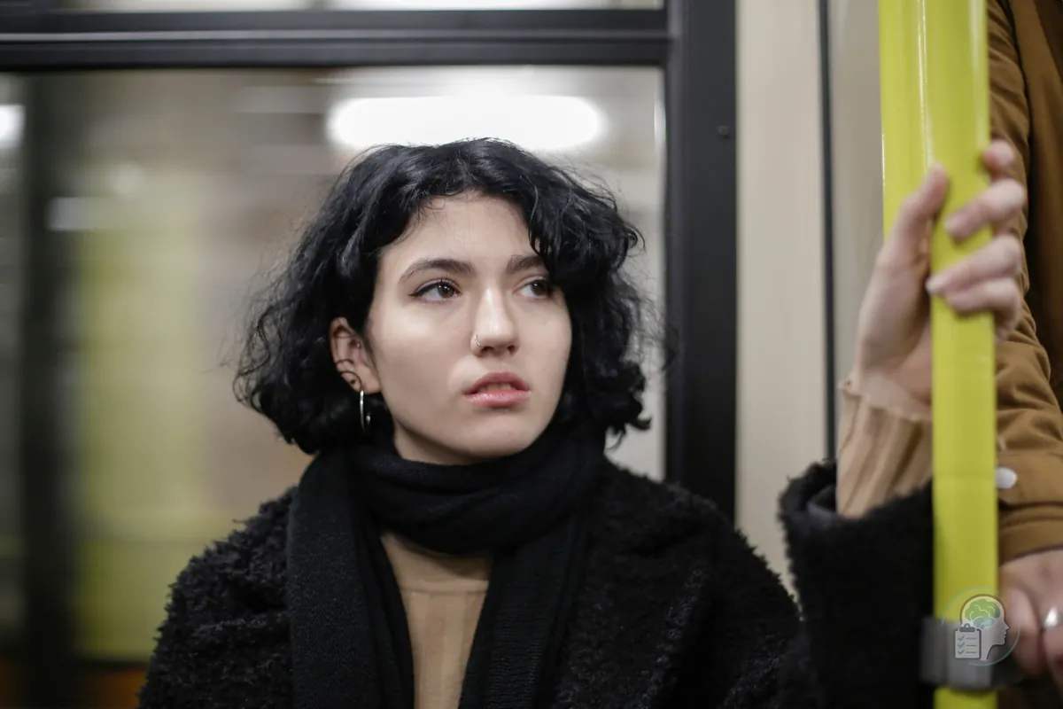 Mujer joven de pie en un vagón de metro agarrada a la barra, uno de los lugares que muchas personas con ataques de pánico aprenden a recuperar en terapia