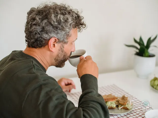 Hombre desayunando solo en la cocina de casa un día laborable durante una baja por ansiedad