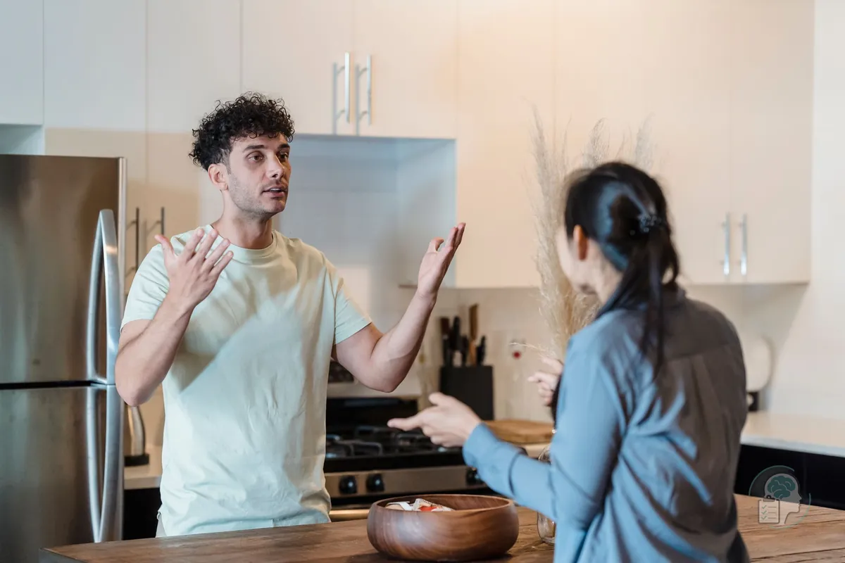 Pareja que discute en la cocina de casa, él con los brazos abiertos y ella de espaldas, uno de los efectos de los cambios de humor bruscos en las relaciones