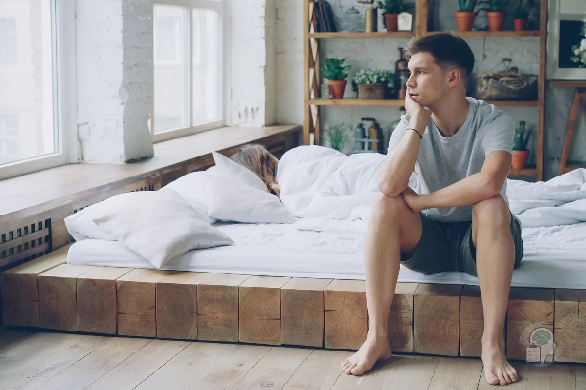 Hombre sentado al borde de la cama por la mañana sin energía para empezar el día