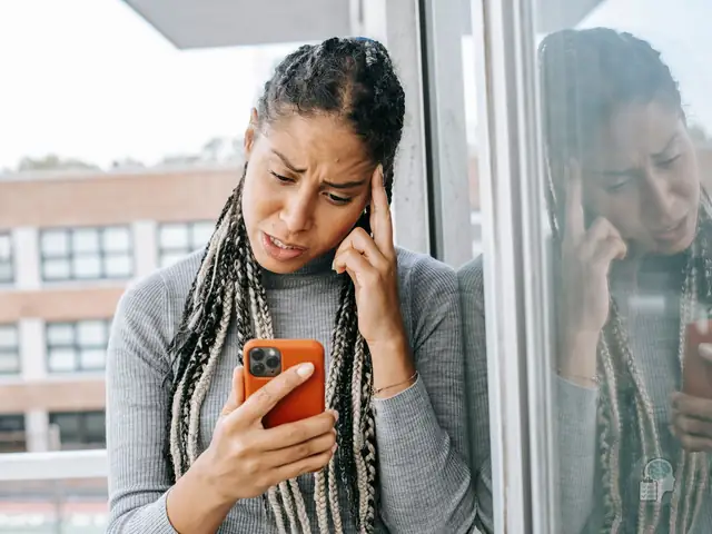 Mujer preocupada leyendo un mensaje en el móvil, una situación frecuente en el maltrato psicológico en la pareja