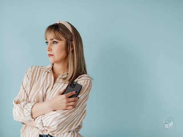 Mujer que aprieta el móvil contra el pecho y aparta la mirada con gesto de duda, una imagen del miedo a hablar por teléfono