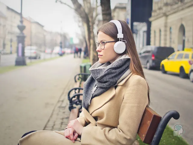 Mujer adulta con auriculares sentada en un banco de la calle gestionando el entorno sensorial
