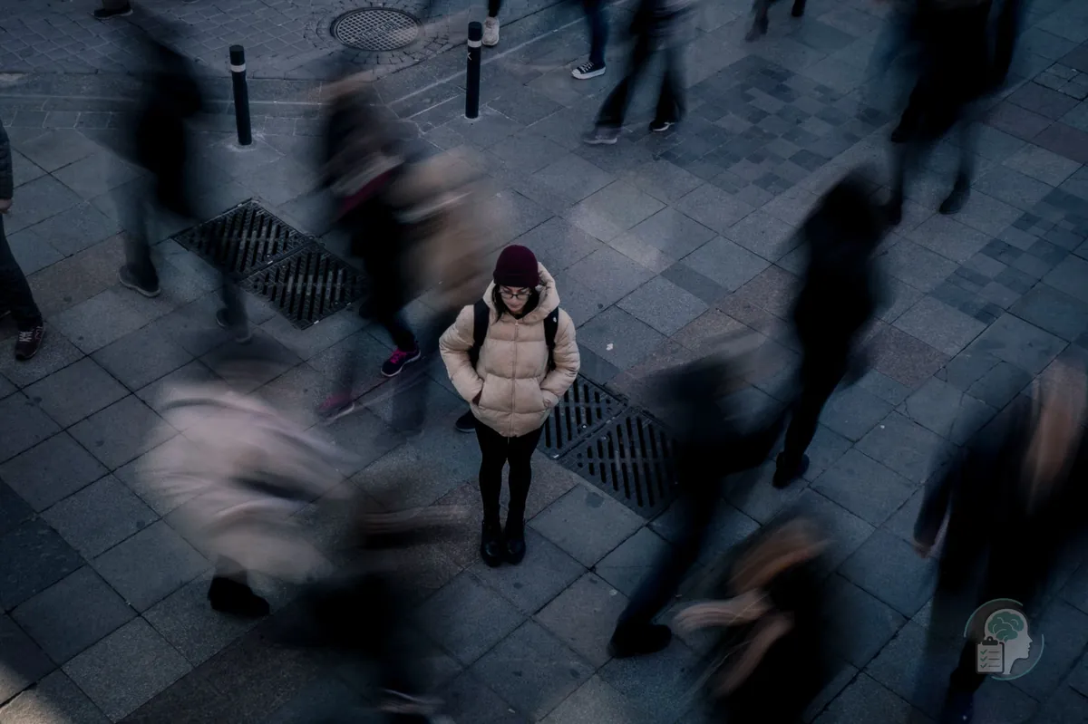 Woman standing still in the middle of a busy street while the crowd blurs past around her