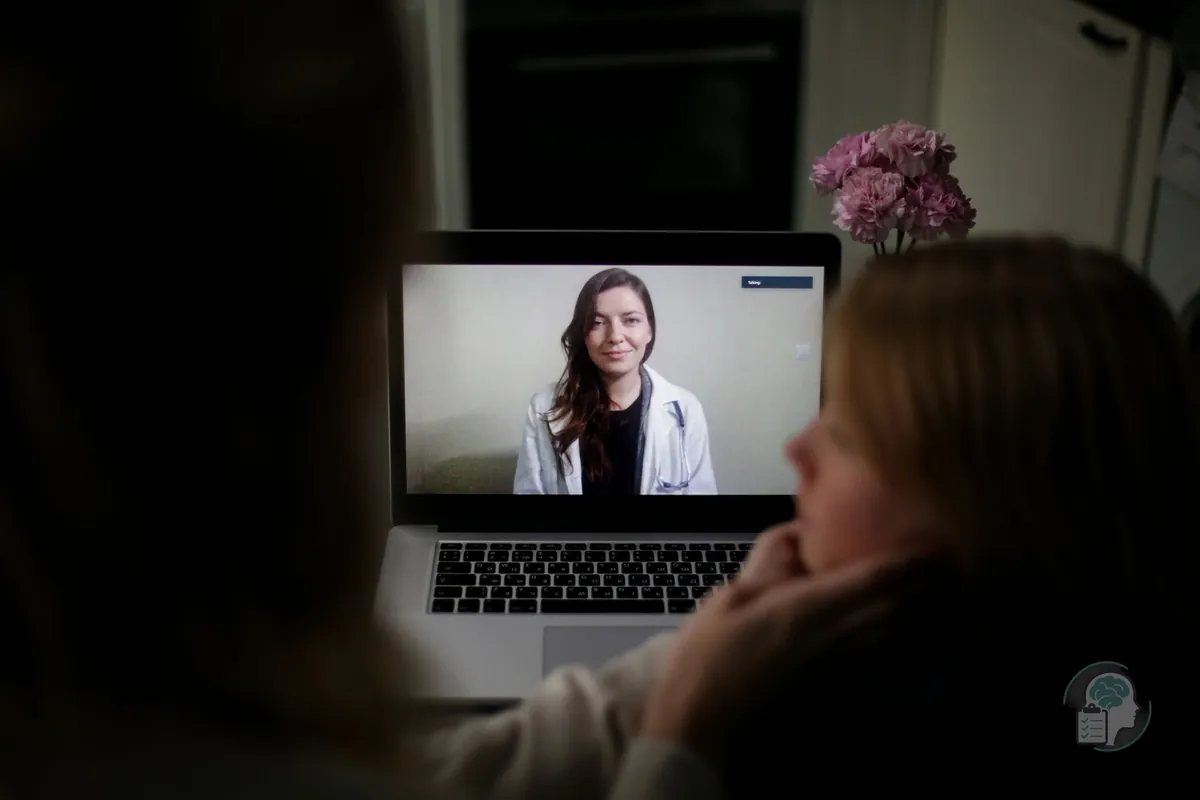 Mujer en una sesión de terapia con su psicóloga online, visible en la pantalla del portátil durante la videollamada