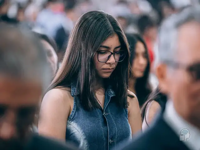Joven con gafas que baja la mirada en medio de una multitud, una imagen de la ansiedad social