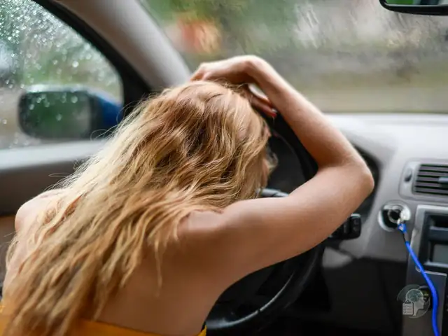 Mujer apoyada en el volante con la mano en la cabeza dentro de un coche, una imagen del miedo a conducir o amaxofobia