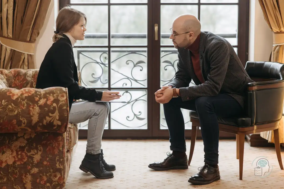 Sesión de terapia en la que una psicóloga y un paciente conversan sentados frente a frente, una imagen del tratamiento psicológico del trastorno bipolar