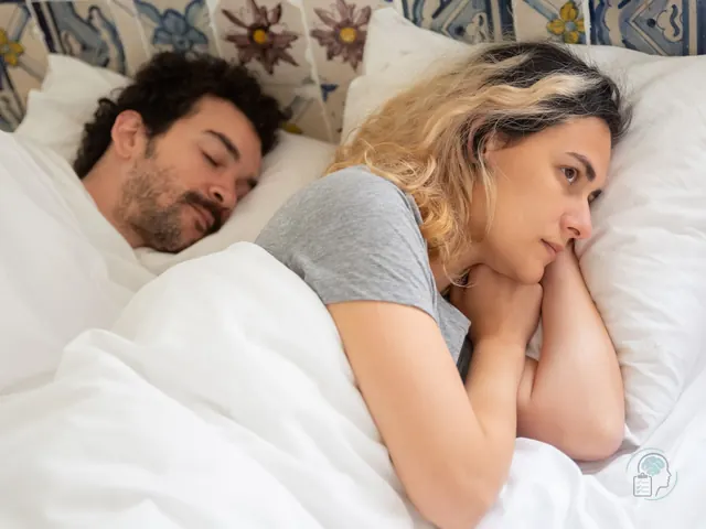 Mujer despierta en la cama de madrugada dándole vueltas a un pensamiento mientras su pareja duerme