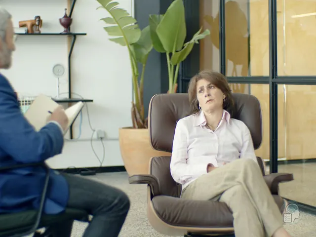 Paciente sentada en el sillón de la consulta con expresión dubitativa mientras su psicólogo toma notas