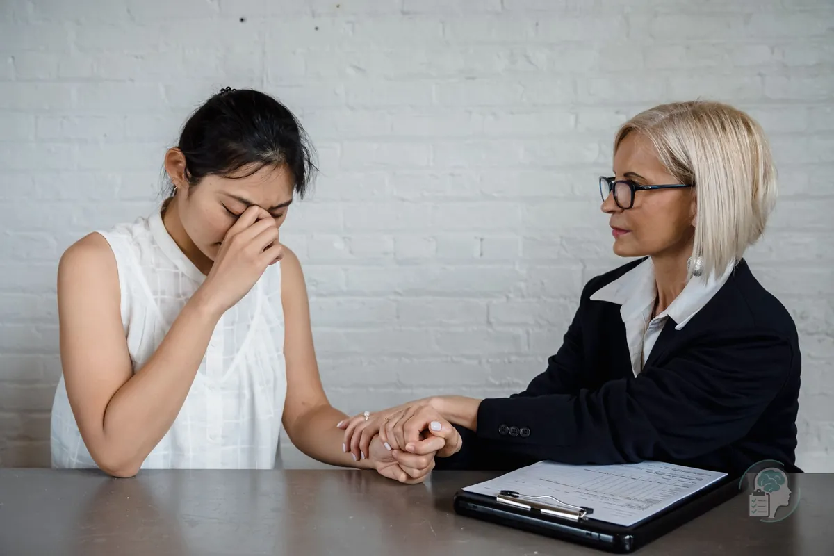 Psicóloga que sostiene la mano de una paciente que llora durante la sesión, como en la validación emocional de la terapia dialéctico-conductual