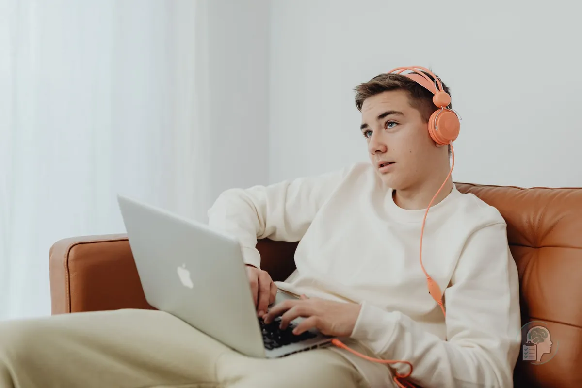 Adolescente con auriculares y un portátil en el sofá de casa, como en una sesión de terapia online para adolescentes