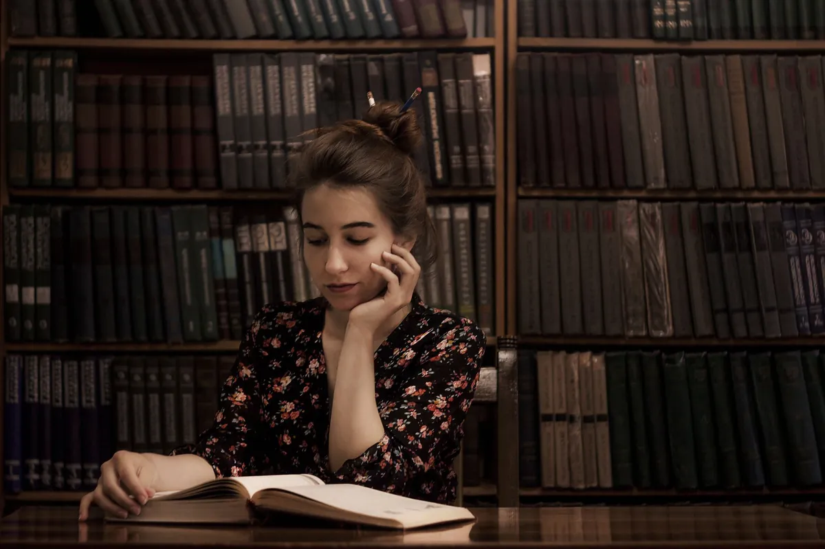 Mujer leyendo pensativa en una biblioteca, ilustrando el test de altas capacidades en adultos