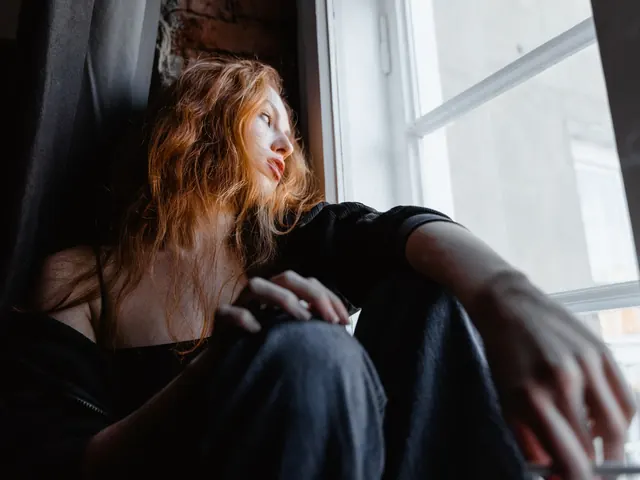 Mujer pensativa sentada junto a una ventana, ilustrando la preocupación y la tensión que mide el test de ansiedad