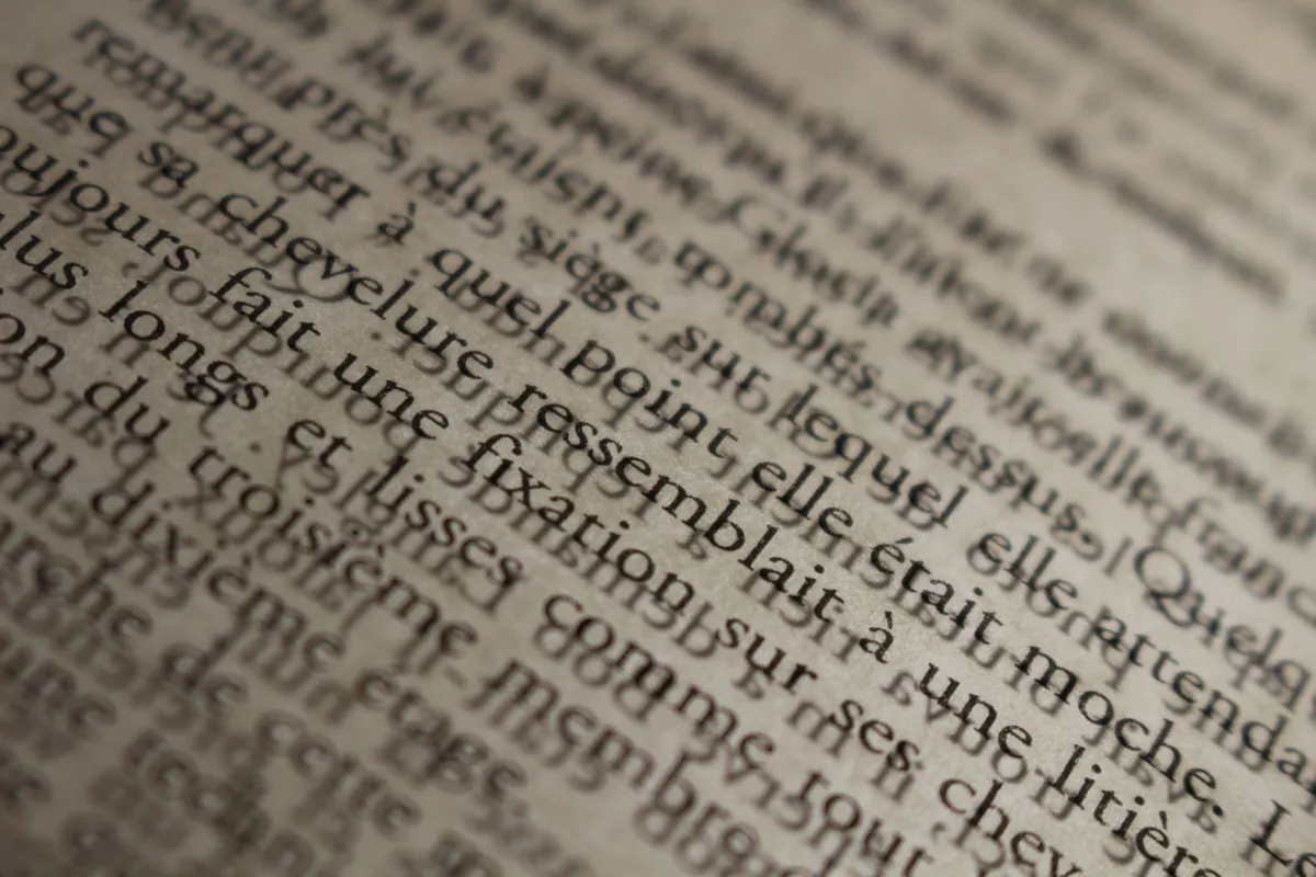 Primer plano de líneas de texto desenfocadas en un libro, que representa la dificultad de lectura de las personas con dislexia