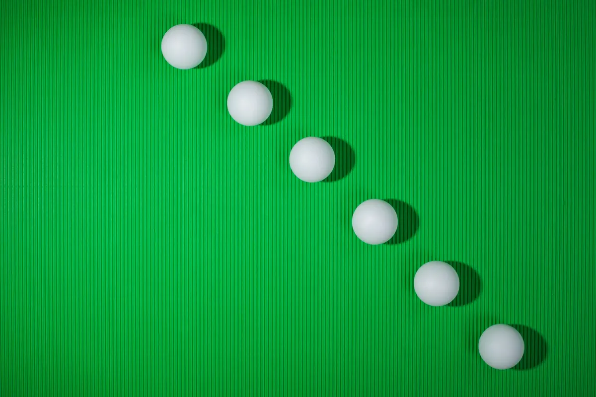 Bolas blancas alineadas en diagonal sobre un fondo verde, símbolo de la necesidad de orden y simetría que valora este test de TOC