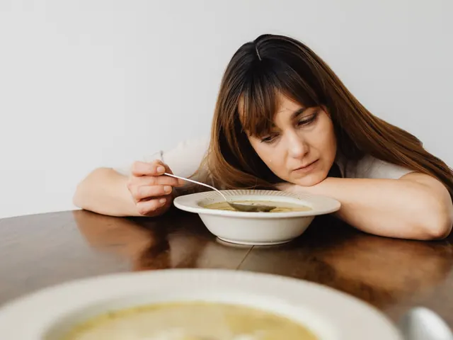 Mujer mirando abatida un plato de sopa sobre la mesa, ilustrando la relación difícil con la comida propia de los trastornos alimentarios (TCA)