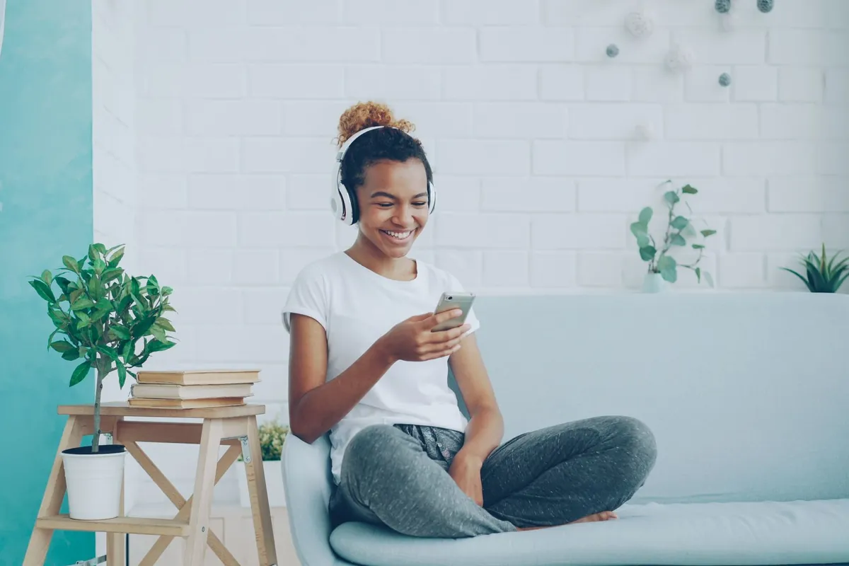 Mujer joven sonriendo mientras hace un test psicológico online desde el sofá con el móvil